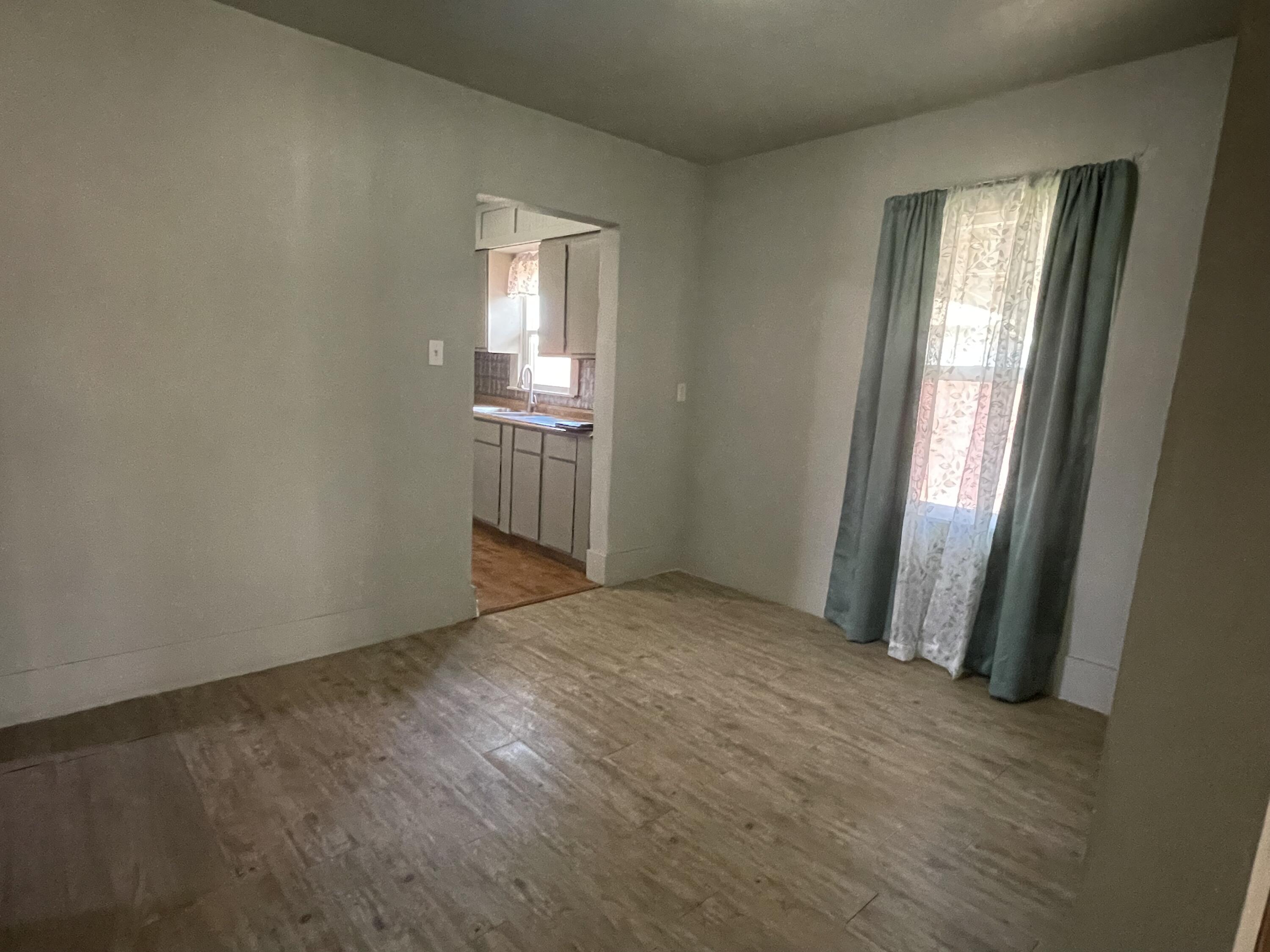 325 South 13th Street Slaton, TX 79364 - Photo 22 of 35 an empty room with wooden floor and windows