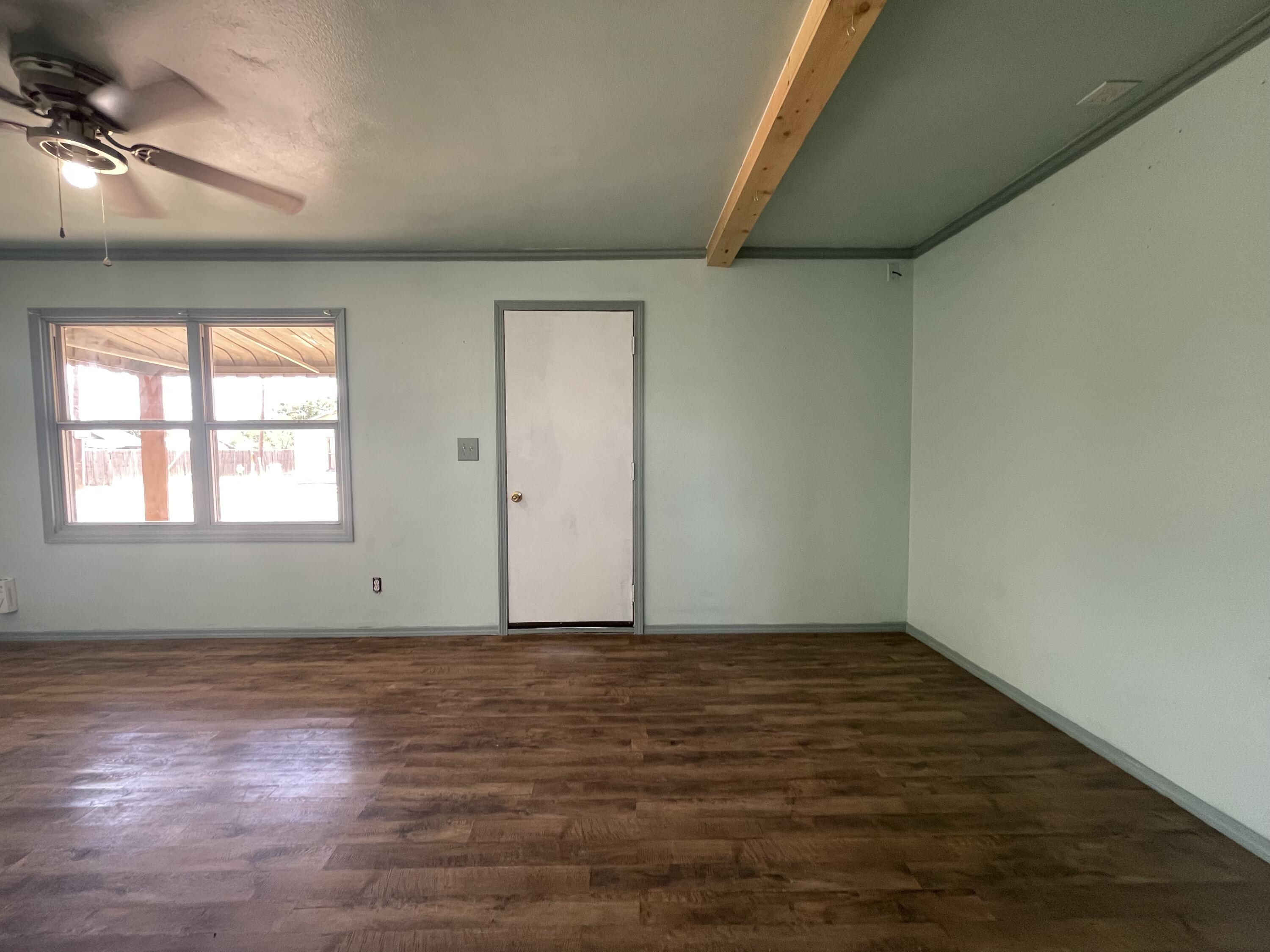 325 South 13th Street Slaton, TX 79364 - Photo 4 of 35 an empty room with wooden floor and windows