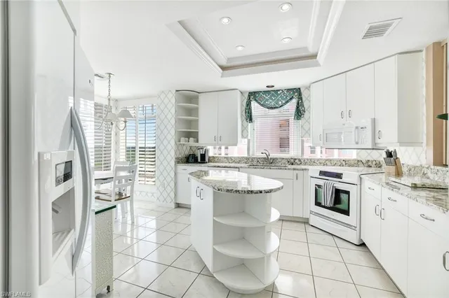 a kitchen with kitchen island granite countertop white cabinets and window
