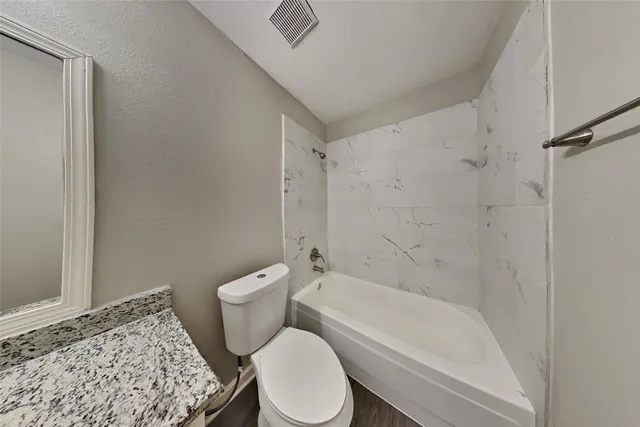 a white toilet sitting next to a bath tub