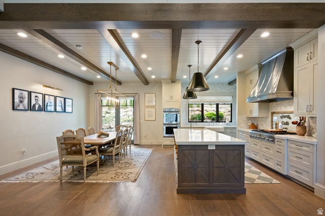 3 Carriagewood Cove, Unit 1088 Sandy, UT 84092 - Photo 19 of 79 Open-concept living space featuring wood-finish flooring, a coffered ceiling with recessed lighting and exposed beams, and a dining area with a brass chandelier