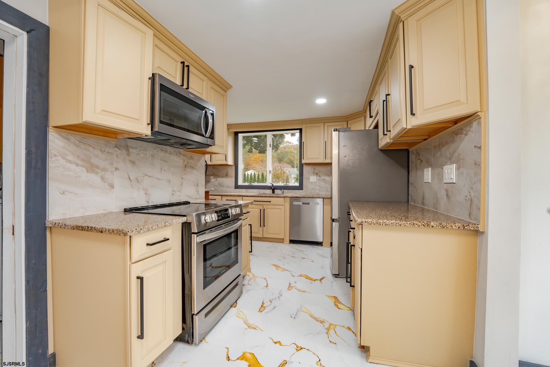 1203 West Mill Road Northfield, NJ 08225 - Photo 14 of 90 a kitchen with stainless steel appliances granite countertop a stove a sink and a microwave