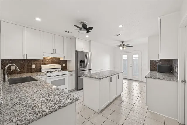 a kitchen with stainless steel appliances granite countertop a stove refrigerator sink and microwave