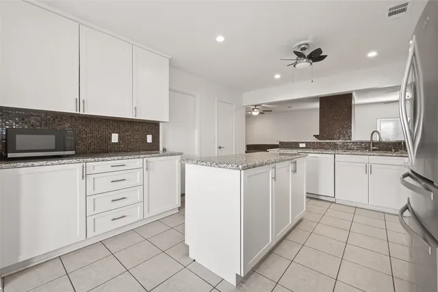a view of a kitchen with a sink and dishwasher with white cabinets