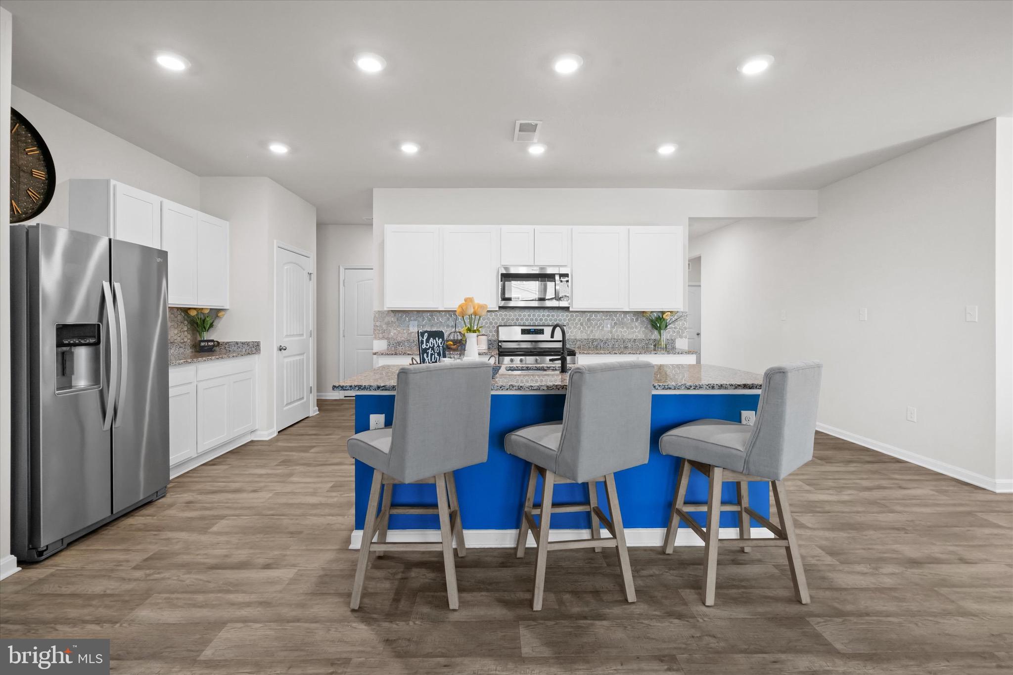 735 Red Maple Road Smyrna, DE 19977 - Photo 16 of 42 a kitchen with stainless steel appliances kitchen island granite countertop a dining table chairs refrigerator and sink