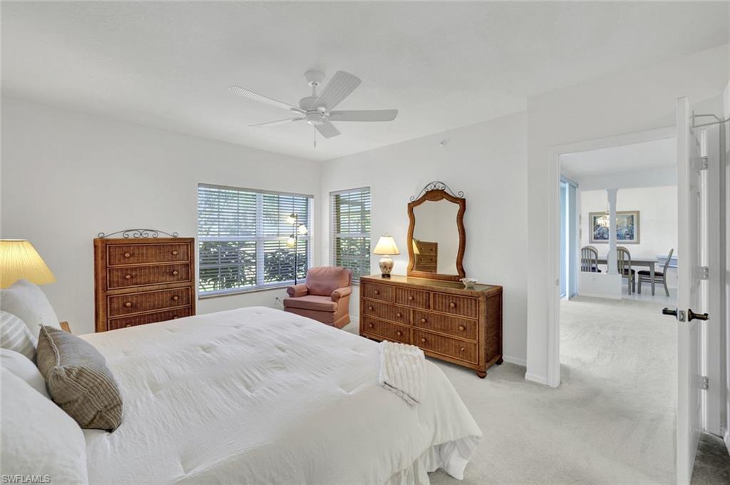 6883 Redbay Park Road, Unit 102 Naples, FL 34109 - Photo 10 of 22 a bedroom with a bed dresser and a flat screen tv