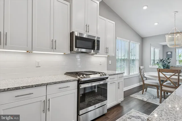 a kitchen with granite countertop white cabinets stainless steel appliances and a counter space