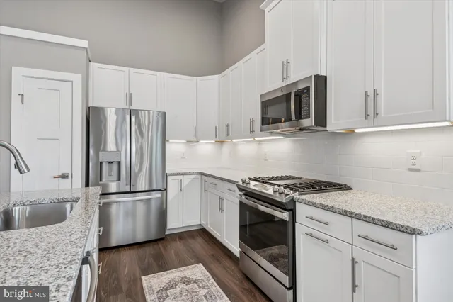 a kitchen with granite countertop a sink stove and refrigerator