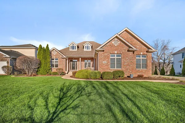 front view of a brick house with a large window and potted plants