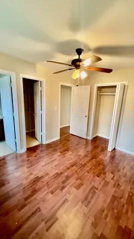a view of empty room with wooden floor and fan