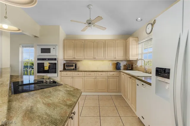 a kitchen with granite countertop a refrigerator oven a sink a stove and cabinets