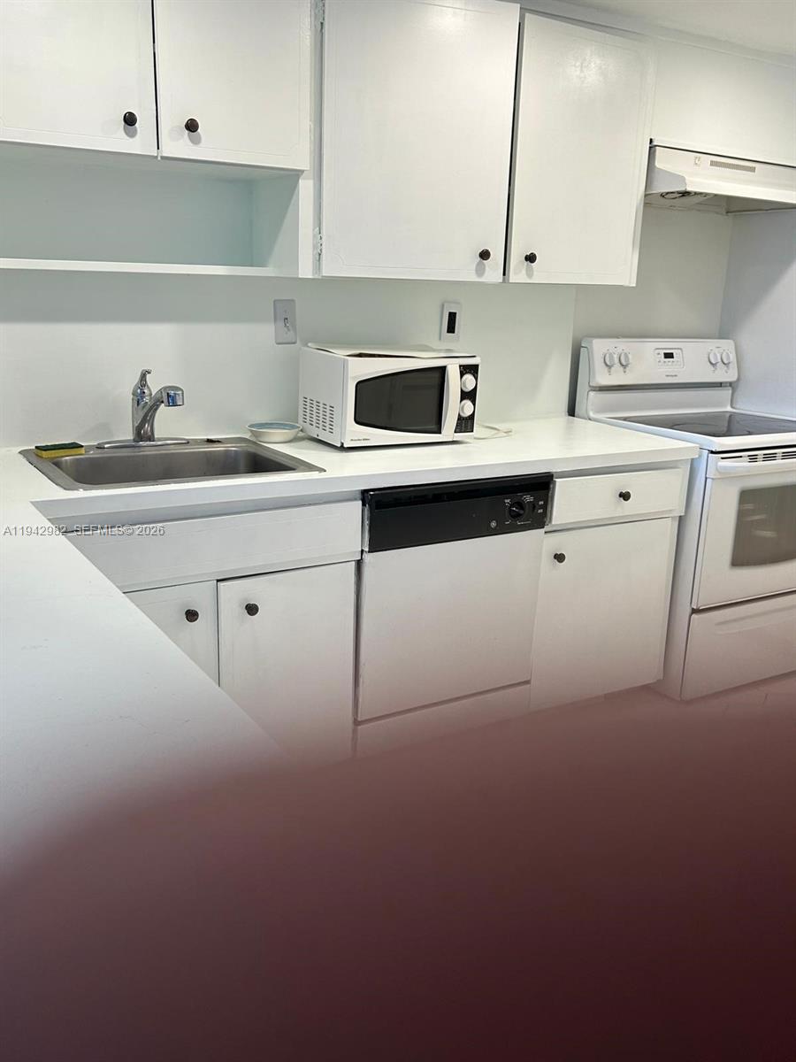 1150 Northeast 191st Street, Unit 45 Miami, FL 33179 - Photo 5 of 10 a kitchen with a sink a stove and cabinets