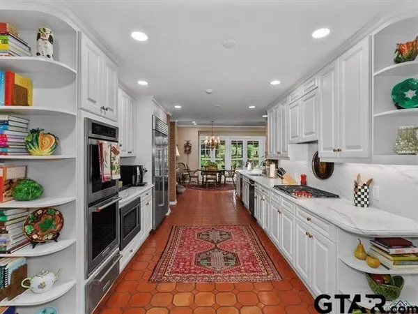 a large kitchen with stainless steel appliances granite countertop a lot of counter space and wooden floor
