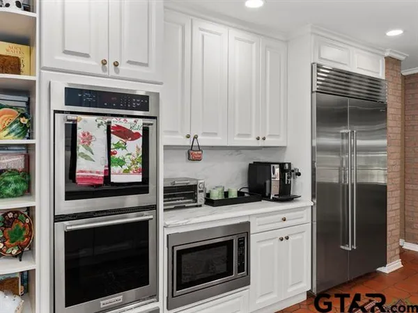 a kitchen with stainless steel appliances white cabinets and a stove top oven