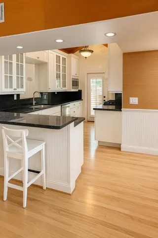 a large kitchen with stainless steel appliances wooden floor and a counter top space
