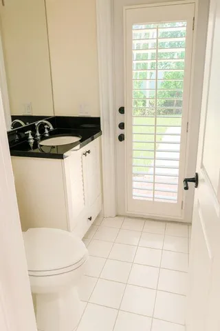 a bathroom with a granite countertop sink a toilet a window and vanity
