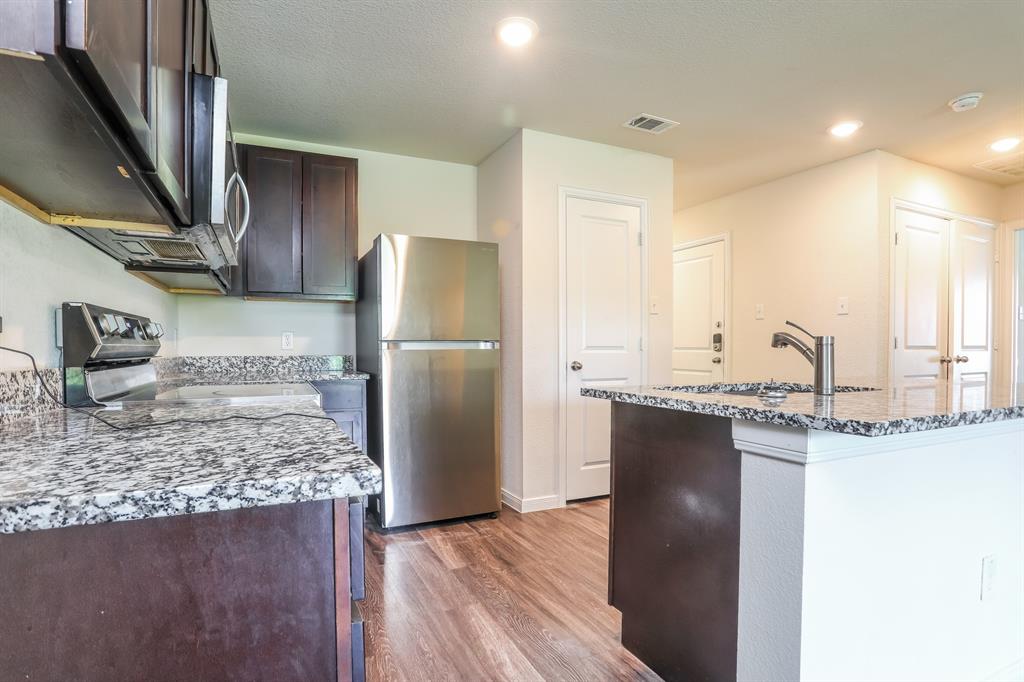2515 Lyle Avenue Waco, TX 76708 - Photo 7 of 21 a kitchen with kitchen island granite countertop a refrigerator a stove and a sink