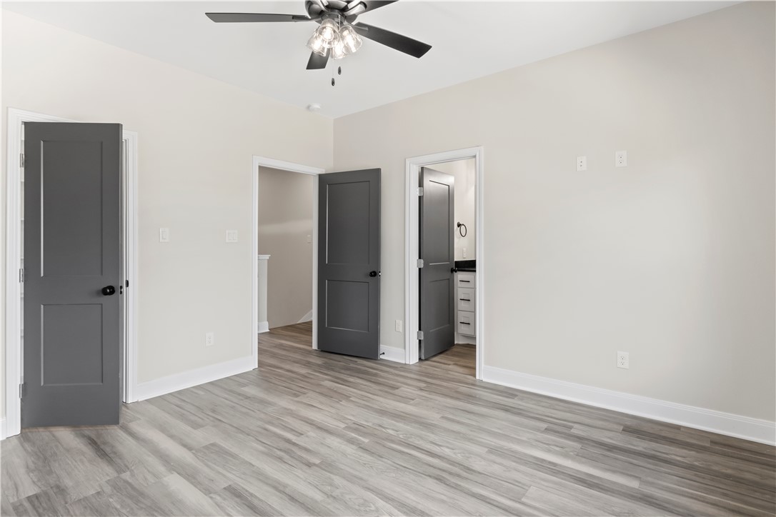 11001-11005 Breedlove Road College Station, TX 77845 - Photo 34 of 40 Unfurnished bedroom featuring light wood-style flooring, ensuite bath, and ceiling fan