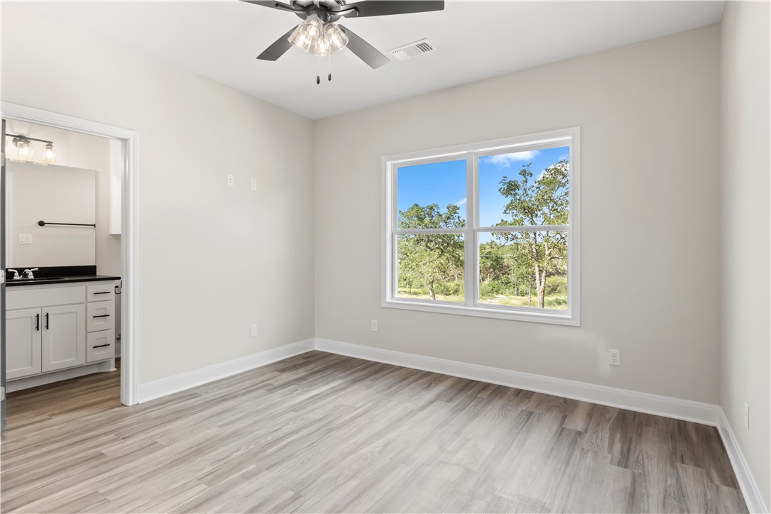 11001-11005 Breedlove Road College Station, TX 77845 - Photo 35 of 40 Unfurnished bedroom with light wood-type flooring, ceiling fan, and ensuite bathroom