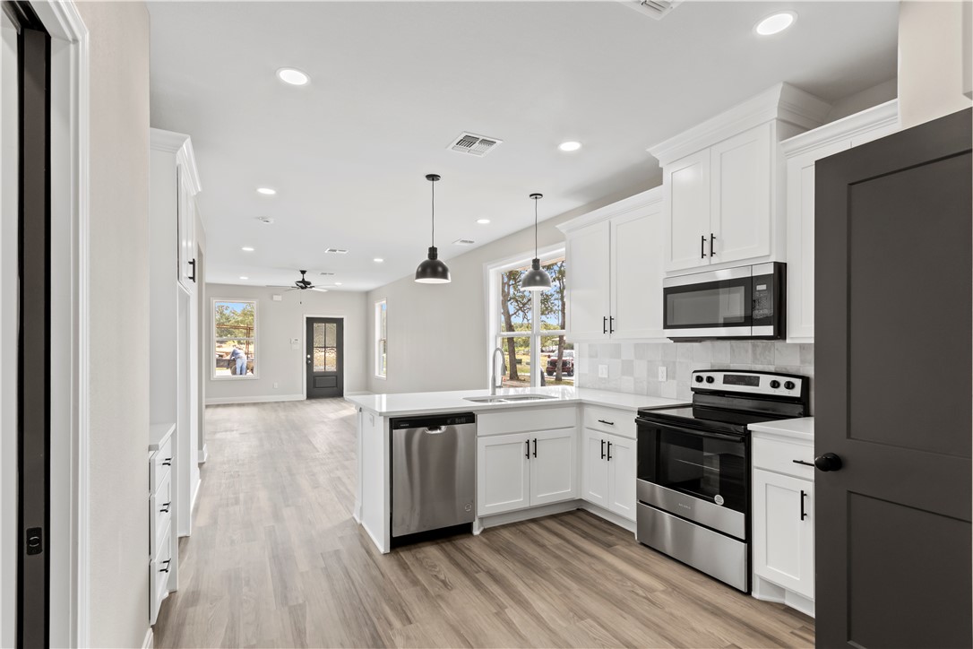 11001-11005 Breedlove Road College Station, TX 77845 - Photo 40 of 40 Kitchen featuring open floor plan, appliances with stainless steel finishes, white cabinetry, recessed lighting, and tasteful backsplash