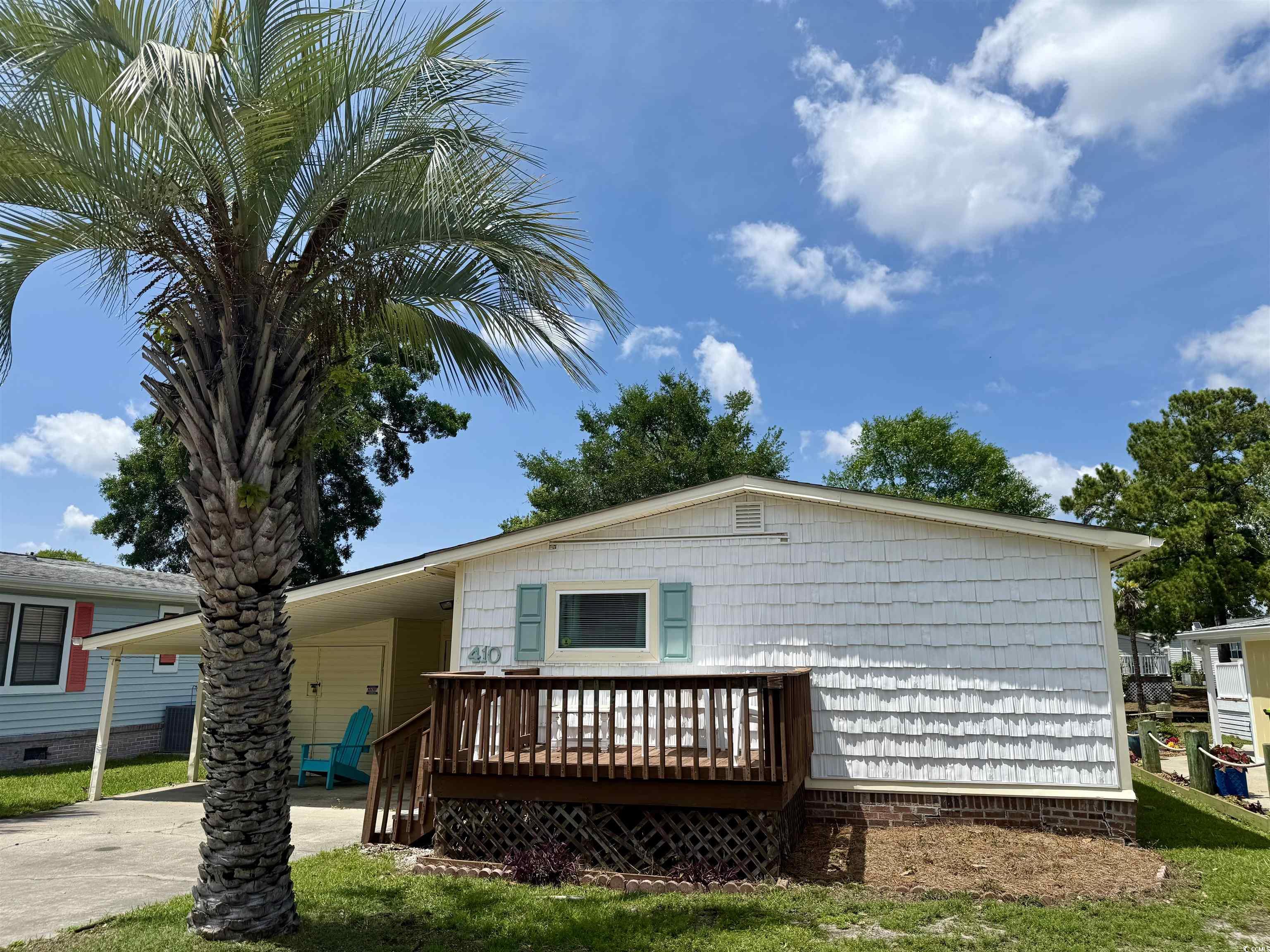View of front of property with driveway, a wooden deck, and a carport