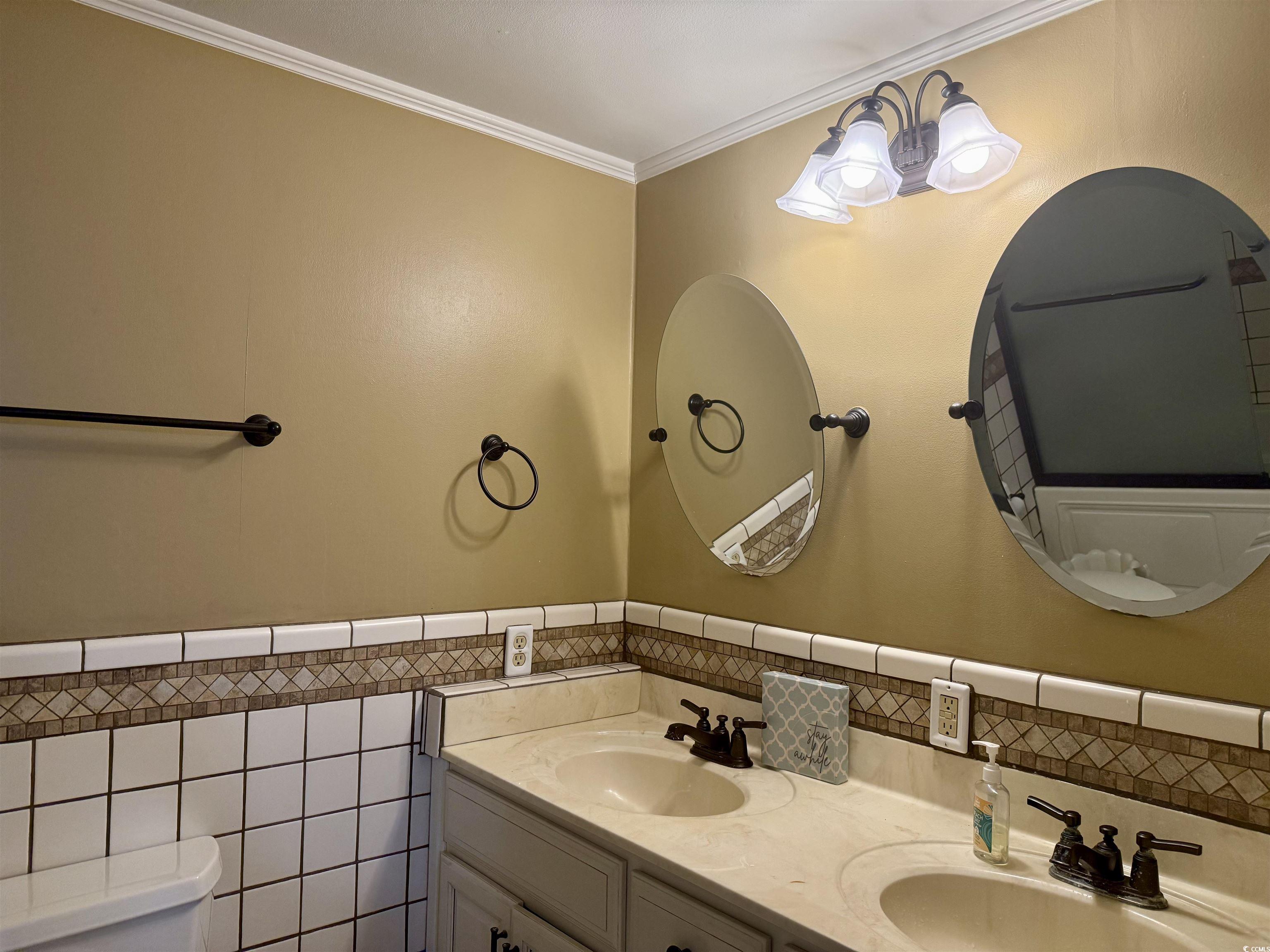 410 E Lake Surfside Beach, SC 29575 - Photo 11 of 27 Full bathroom featuring tile walls, toilet, double vanity, ornamental molding, and a wainscoted wall