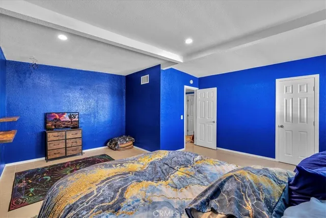 a bedroom with a bed and a lamp on dresser