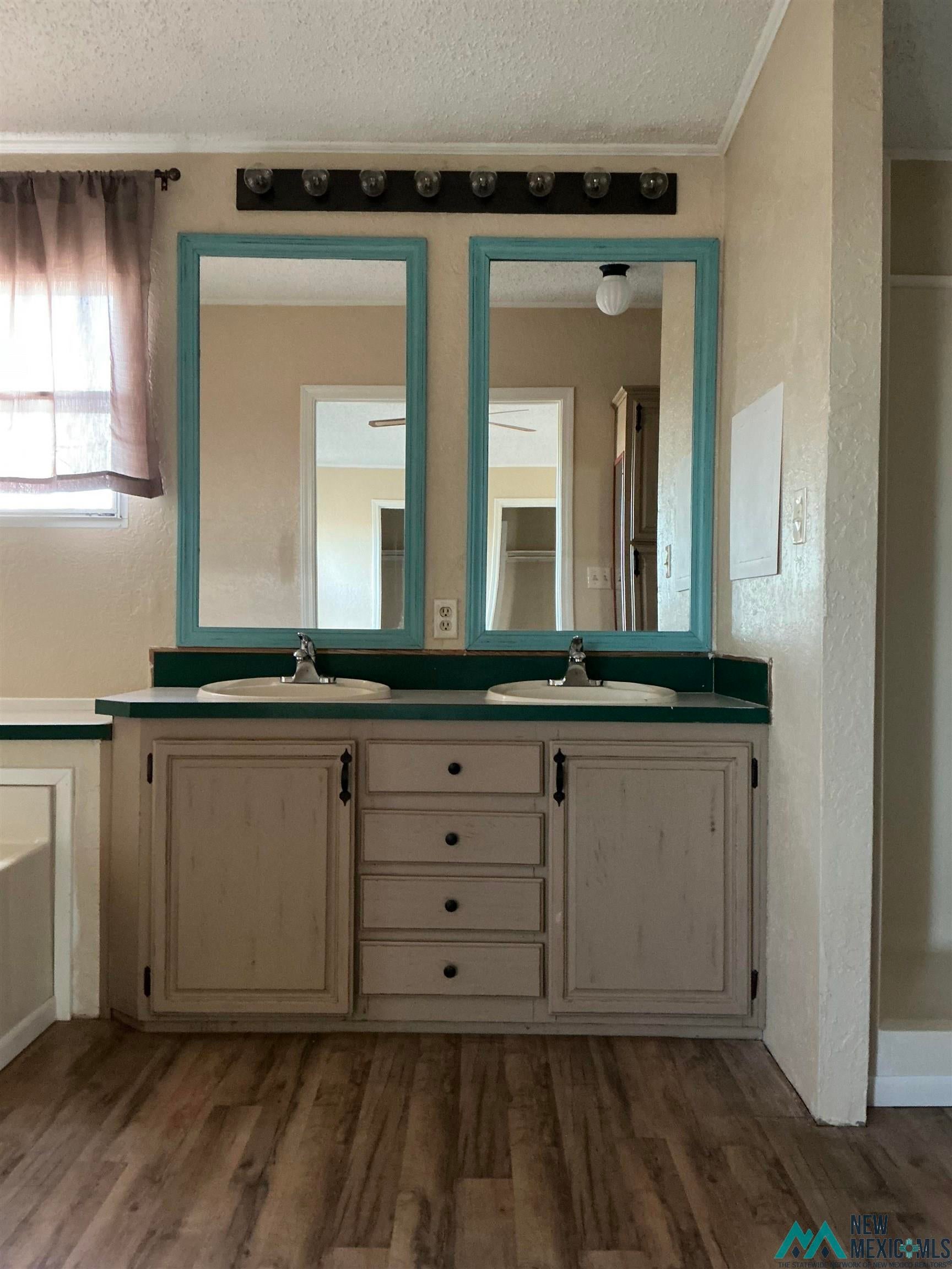 1020 South Fork Road Clovis, NM 88101 - Photo 22 of 37 Bathroom featuring a textured ceiling, double vanity, light wood-type flooring, and a textured wall