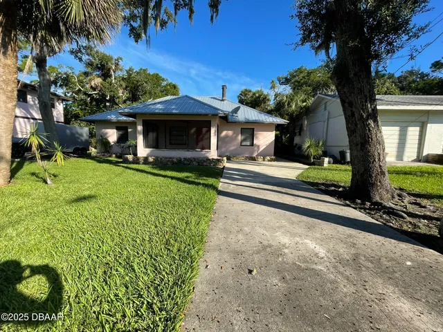 a front view of a house with a yard and potted plants