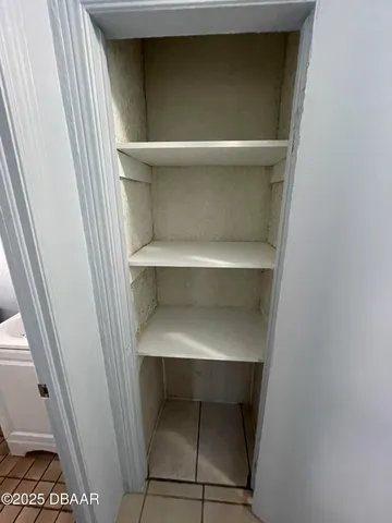 a view of an empty room and window and chandelier fan