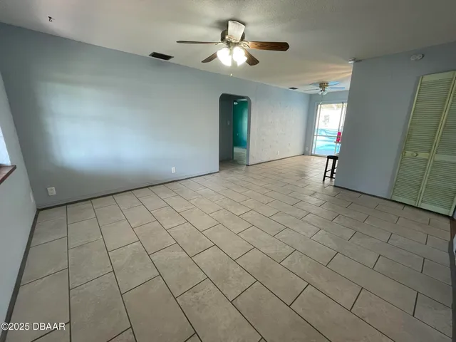 a view of an empty room and chandelier fan