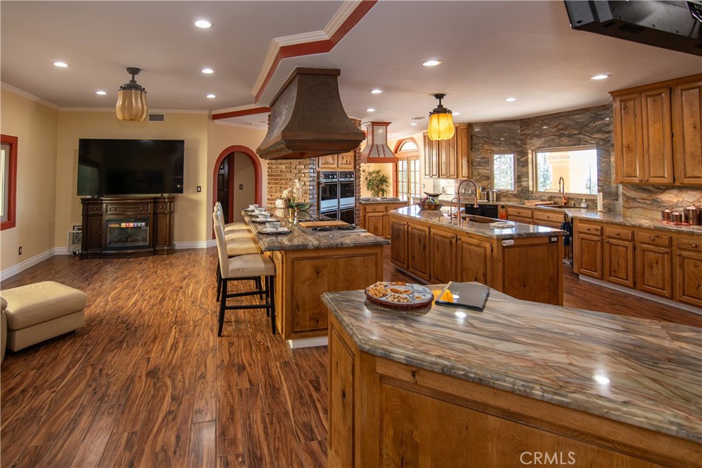 10425 Melvin Avenue Porter Ranch, CA 91326 - Photo 21 of 61 a kitchen with stainless steel appliances kitchen island granite countertop a stove top oven a sink dishwasher a dining table and chairs with wooden floor