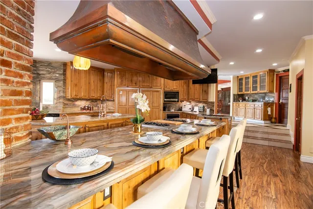 a kitchen with stainless steel appliances granite countertop a sink a stove and a wooden floors