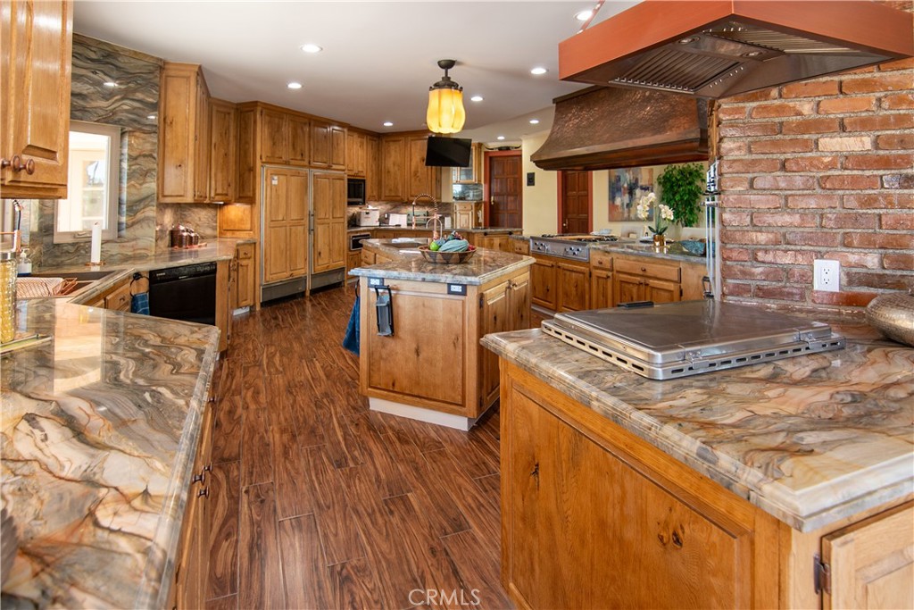10425 Melvin Avenue Porter Ranch, CA 91326 - Photo 35 of 61 a kitchen with kitchen island granite countertop a stove top oven a sink dishwasher and white cabinets with wooden floor