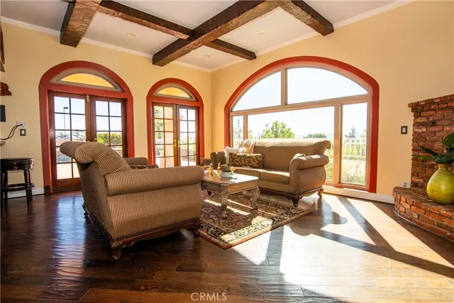 a view of a livingroom with furniture wooden floor a fireplace and windows