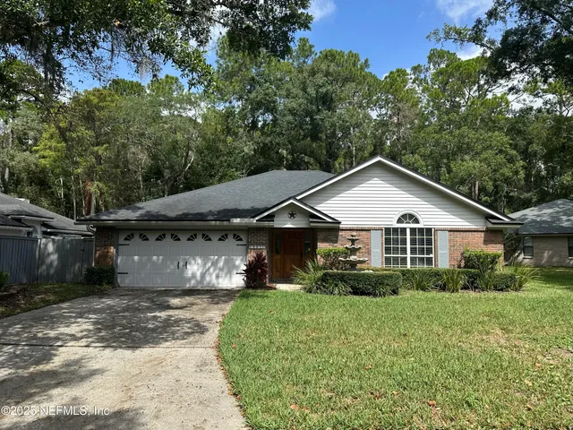 a view of a house with a big yard plants and large trees