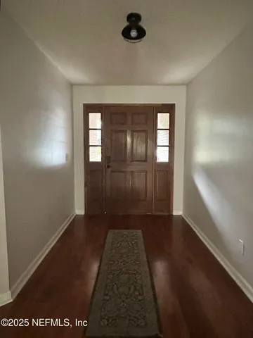 an entryway space with wooden floor and windows