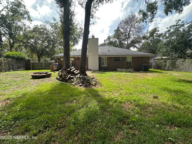 a view of a house with backyard and trees