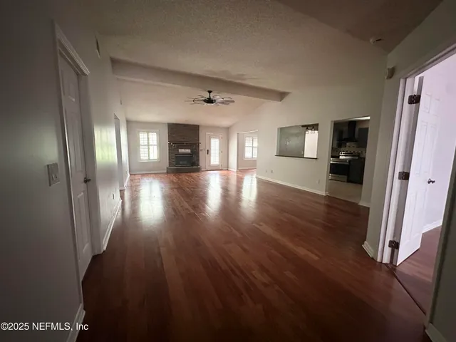 a view of a hallway with wooden floor and windows
