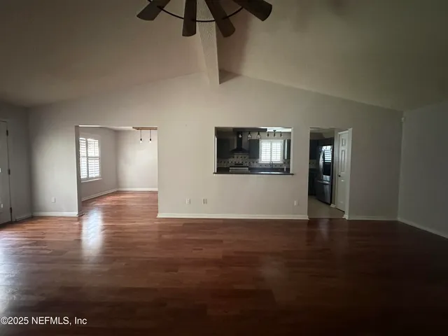 a view of empty room with wooden floor and fan