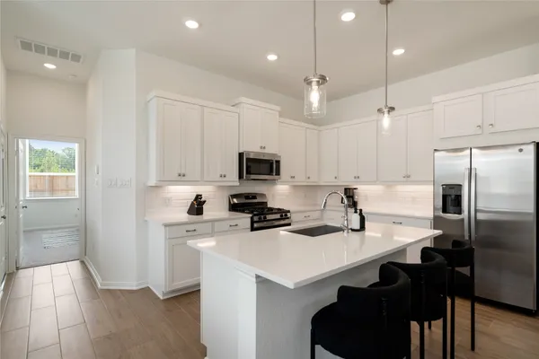a kitchen with a sink a refrigerator and white cabinets