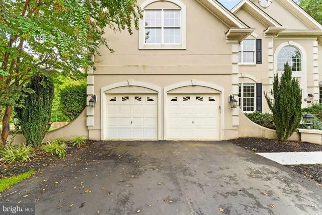 a view of a white house with large windows and a yard with plants