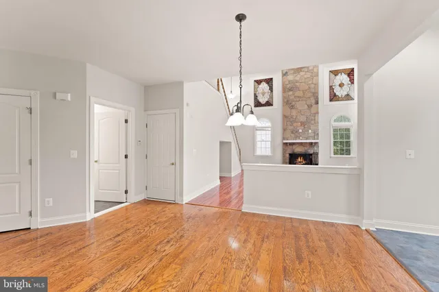a view of an empty room with wooden floor and a ceiling fan