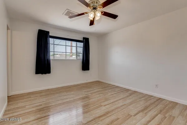a view of an empty room with window and chandelier fan