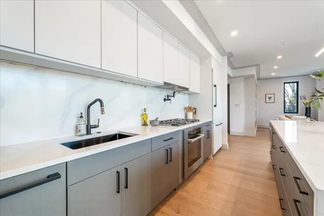 a large kitchen with stainless steel appliances granite countertop a sink and cabinets