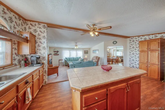 a living room with furniture kitchen view wooden floor and a large window