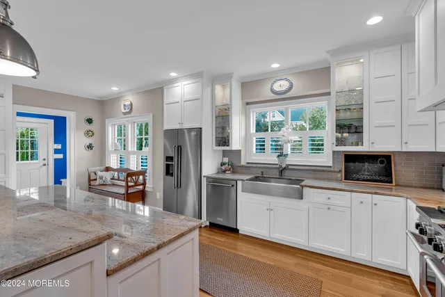 a kitchen with stainless steel appliances a stove a sink a refrigerator white cabinets and a refrigerator