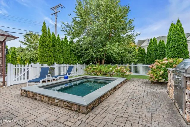 a view of a big yard with a swimming pool and trees in the background