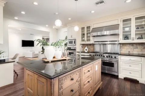 a kitchen with kitchen island granite countertop a sink cabinets and wooden floor