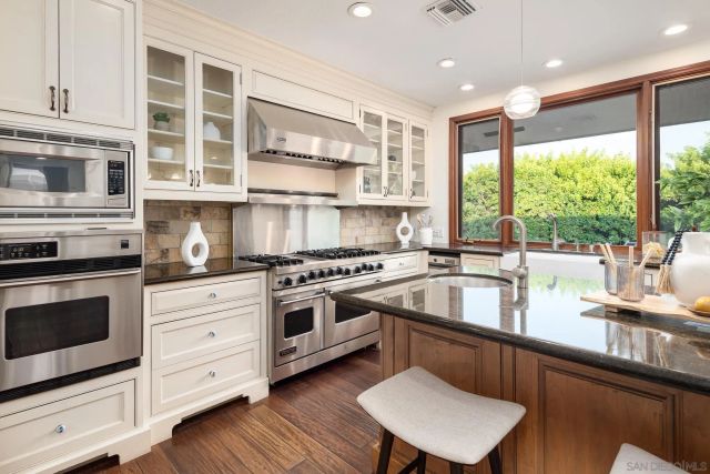 a kitchen with stainless steel appliances granite countertop a stove a sink and a microwave